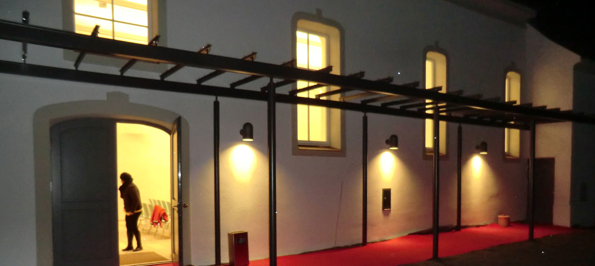 Nächtlich beleuchteter Eingang der Alten Kirche Pleinting